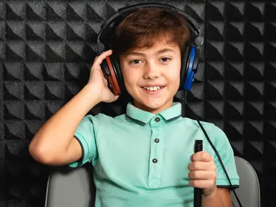 Child wearing headphones and holding a microphone in a soundproof room